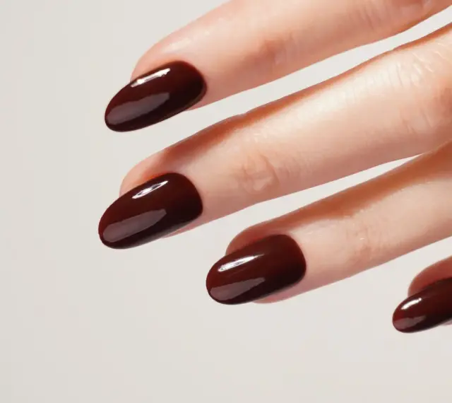 Une idée manucure automne : des ongles courts et arrondis, vernis d'un brun chocolat profond et brillant, évoquant la douceur des feuilles mortes.