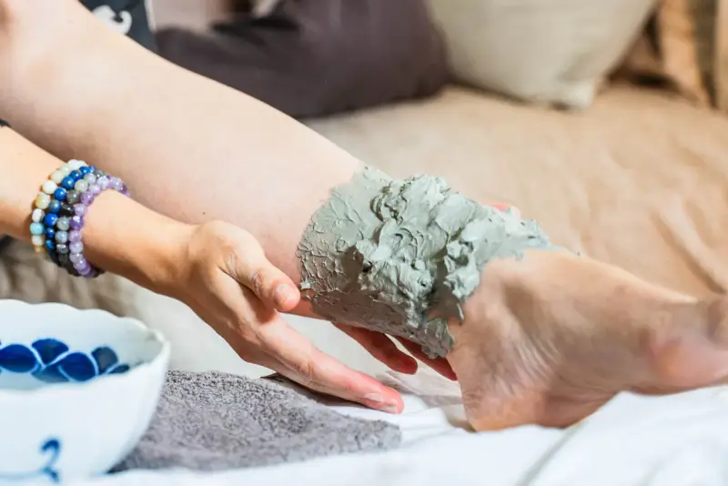 Application d'argile verte sur une jambe, profitant de ses bienfaits détoxifiants et apaisants pour la peau.